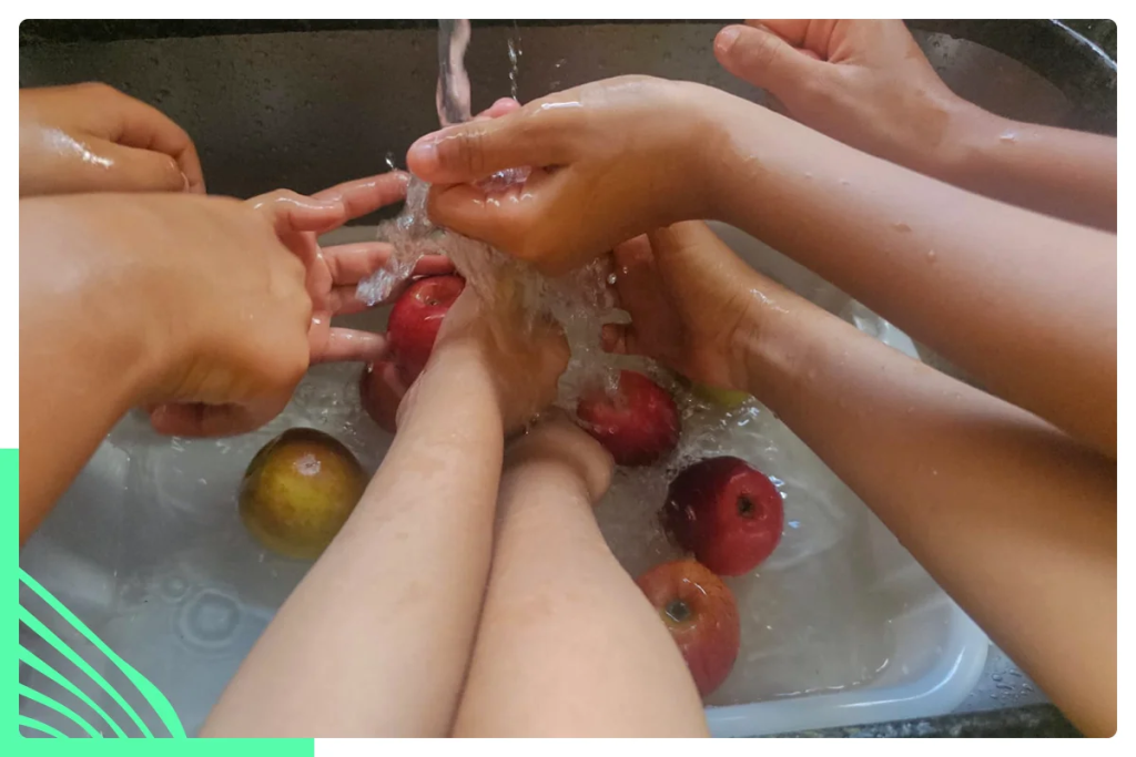Crianças lavam frutas durante atividades no centro recreativo.